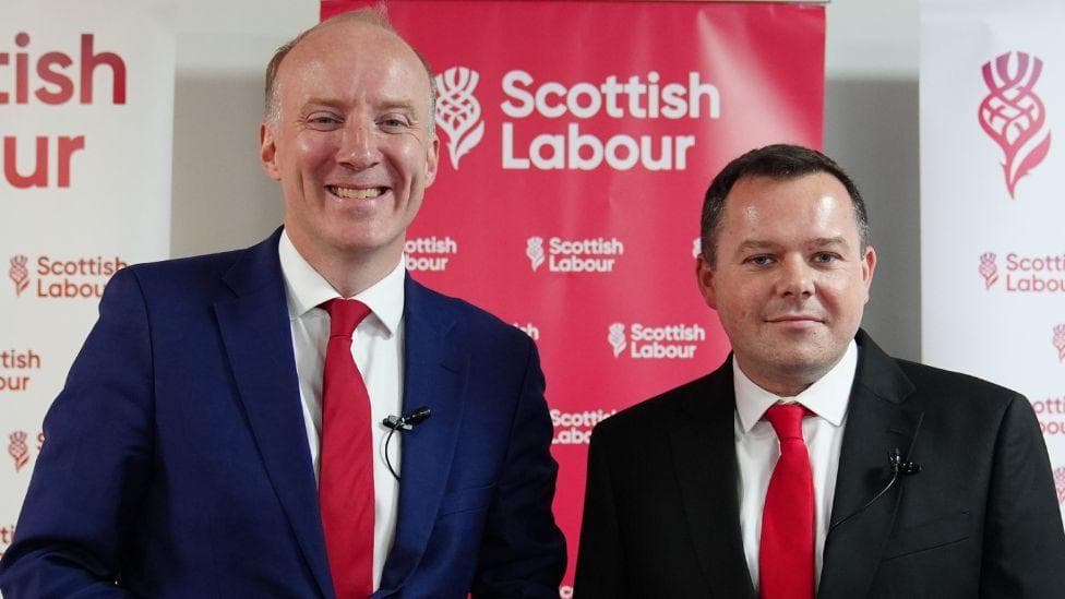 Two men in business suits stand side by side smiling. Marra, on the left, is taller with thinning grey hair. Fagan, on the right, has short dark hair.