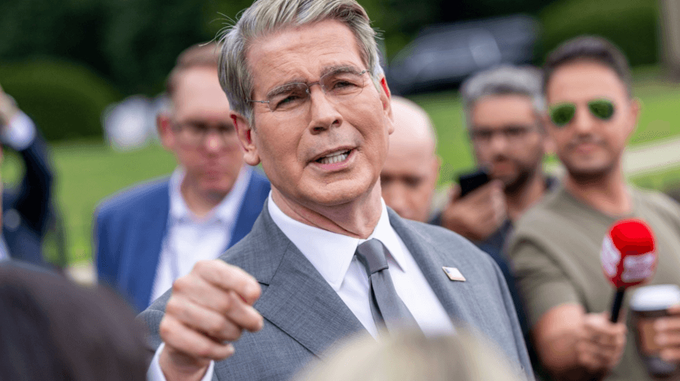 US Treasury Secretary Scott Bessent addresses members of the media on the lawn outside the White House. He's wearing a light grey suit, white shirt and silver tie