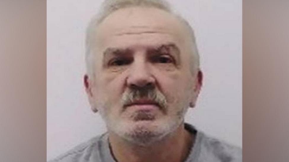 Police mugshot of Eugeniu Neamtu, a man with short grey hair, a beard, and a moustache facing forward