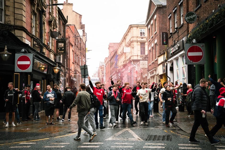 A vibrant street scene of football fans celebrating in Liverpool, England.