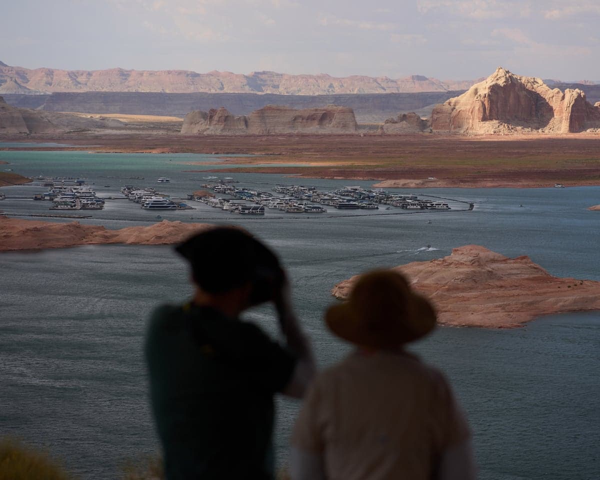 Two people out of focus look out toward water with spots of land showing