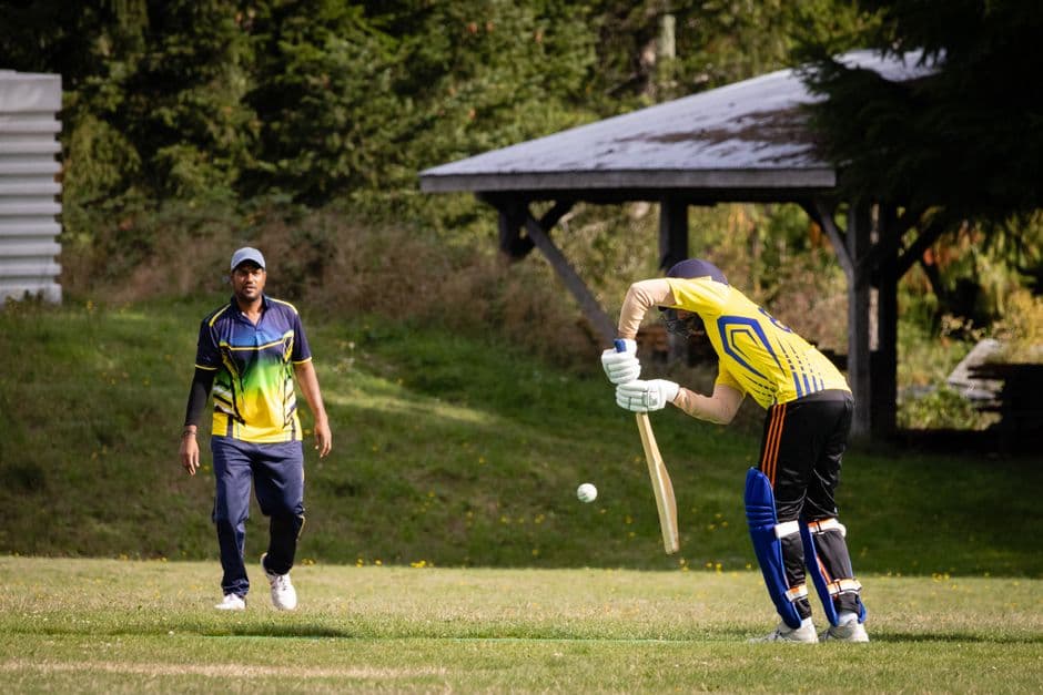 Exciting cricket match with two players in a vibrant outdoor field setting.