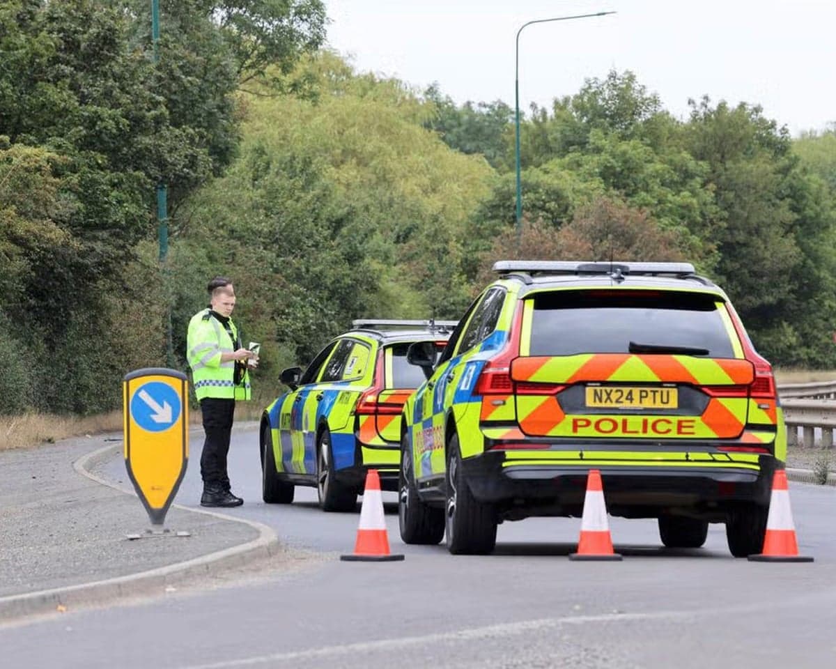 Police officers stand by their vehicles on a blocked road