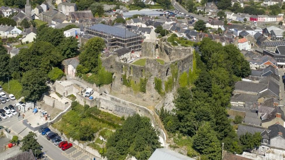 Haverfordwest Castle surrounded by green trees and houses from an aerial view