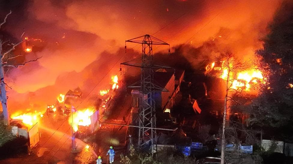 An aerial view of a fire destroying cars and other property at a business park.