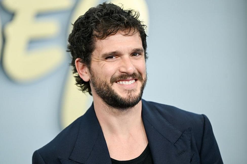Kit Harrington seen smiling on the red carpet in a blue blazer on the red carpet in New York in May.