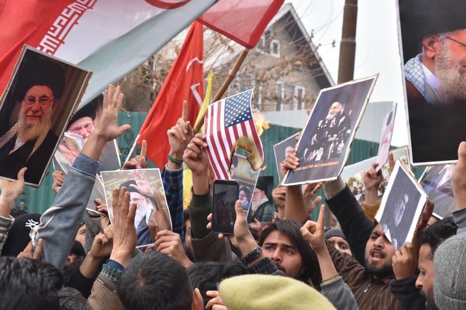 Crowd of demonstrators holding flags and banners during a protest outdoors.