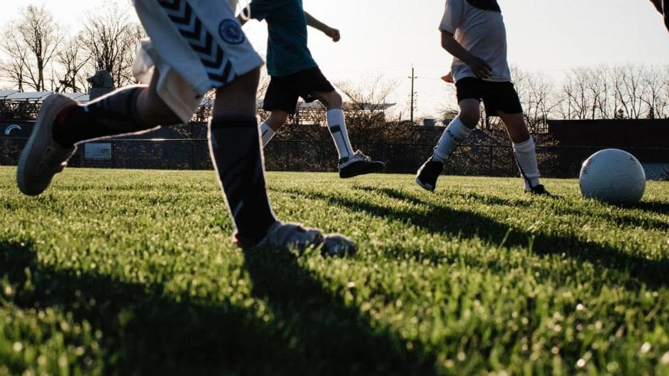a silhouette image of three kids playing football