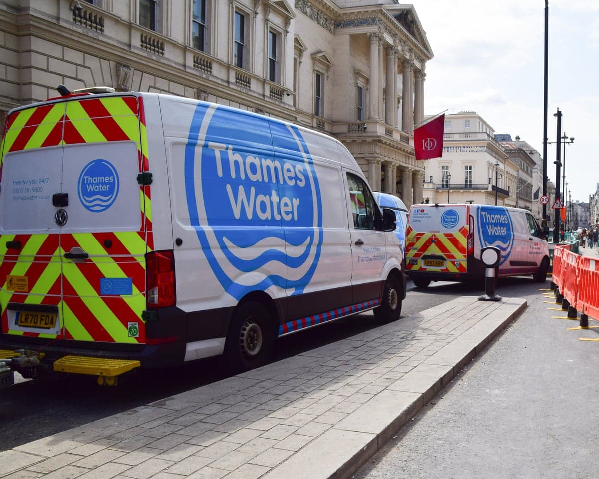 Two Thames Water vans next to orange barriers of repair site.