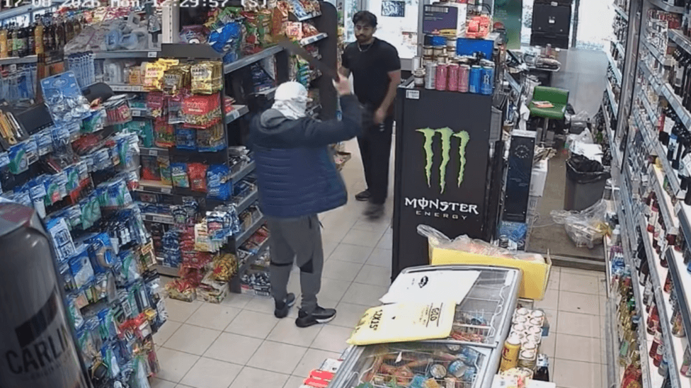 CCTV footage of a shop being robbed by a man with a knife in the air