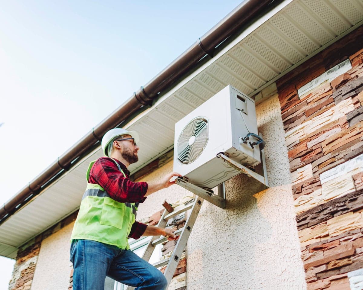 Technician in uniform repairing heat pump