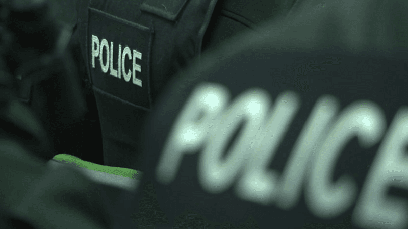 A close-up of the back of police officers' black jackets with police in white letters