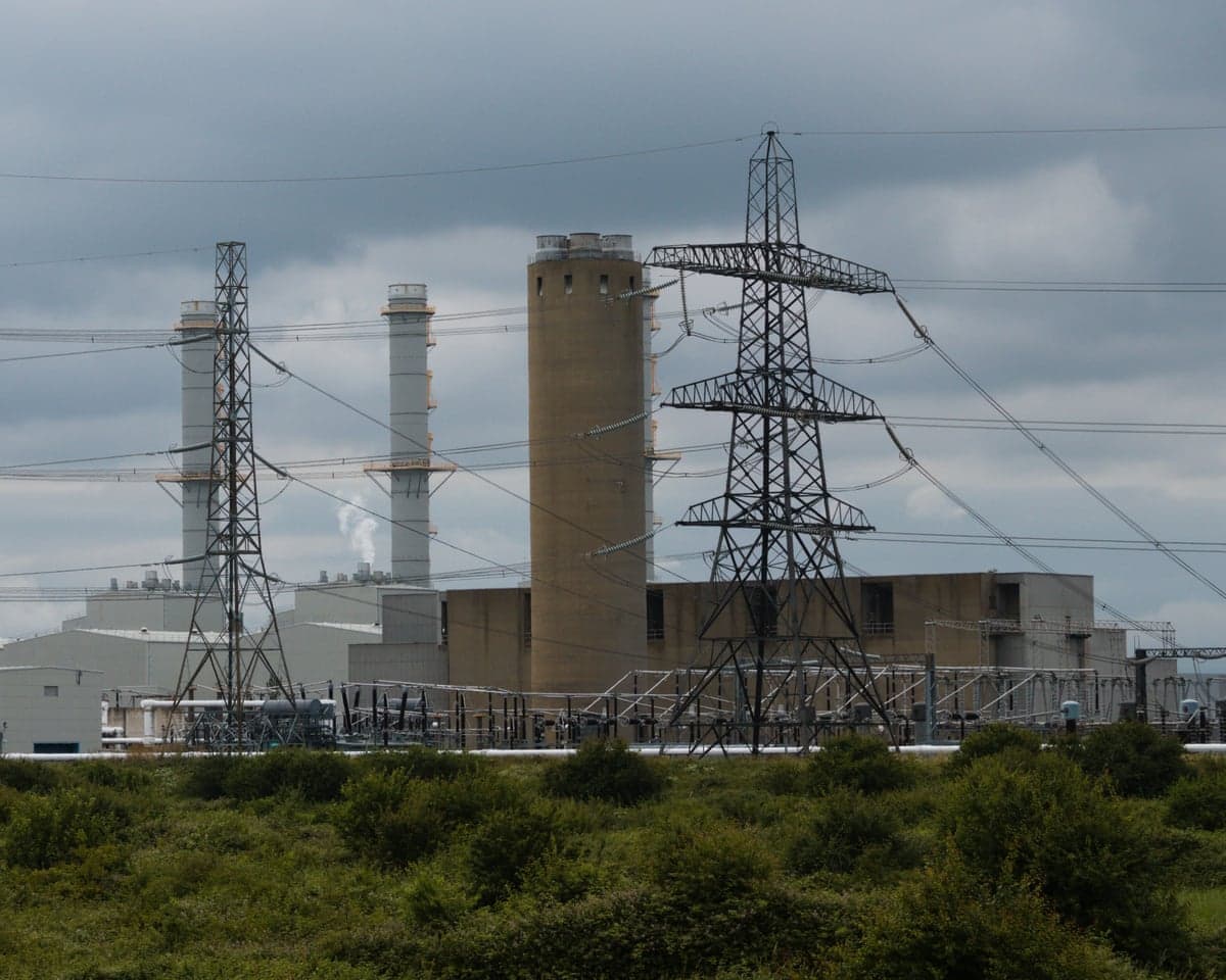 A power plant with chimneys and electrical pylons under cloudy skies