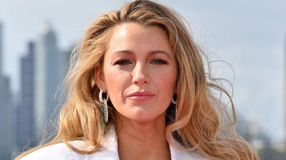 Blake Lively in a white suit and earrings posing in front of the London skyline on 8 August 2024