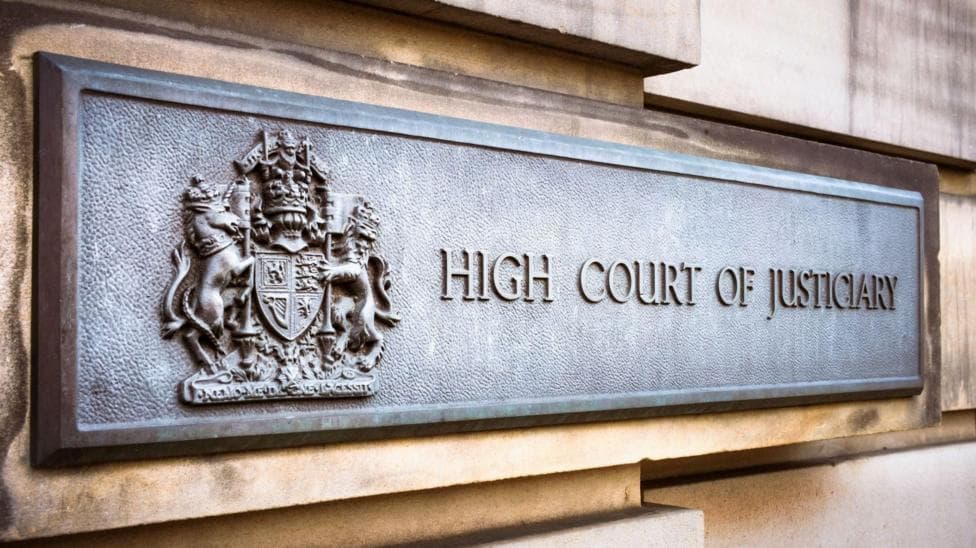Grey sign with an emblem and the words High Court of Justiciary