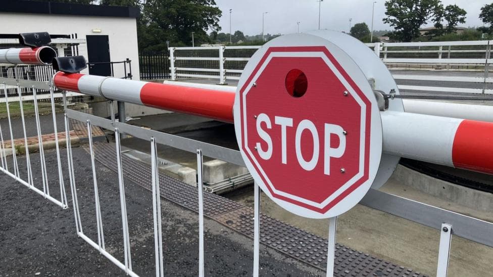 A close-up of a red and white sign on barriers at Torvean Swing Bridge. The sign has the word "stop" in white capital letters.