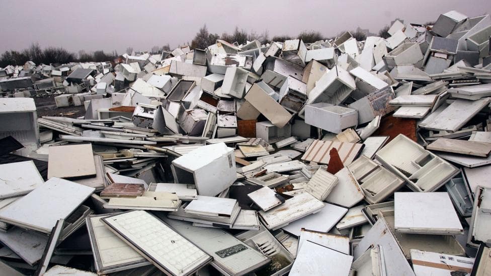 A huge pile of broken fridges is pictured, with white doors removed from some units.