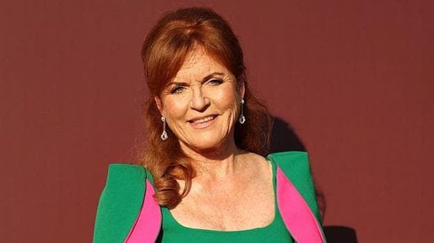 Sarah Ferguson, with her dark red hair half tied up, in a green dress and fuchsia dress and diamond earrings