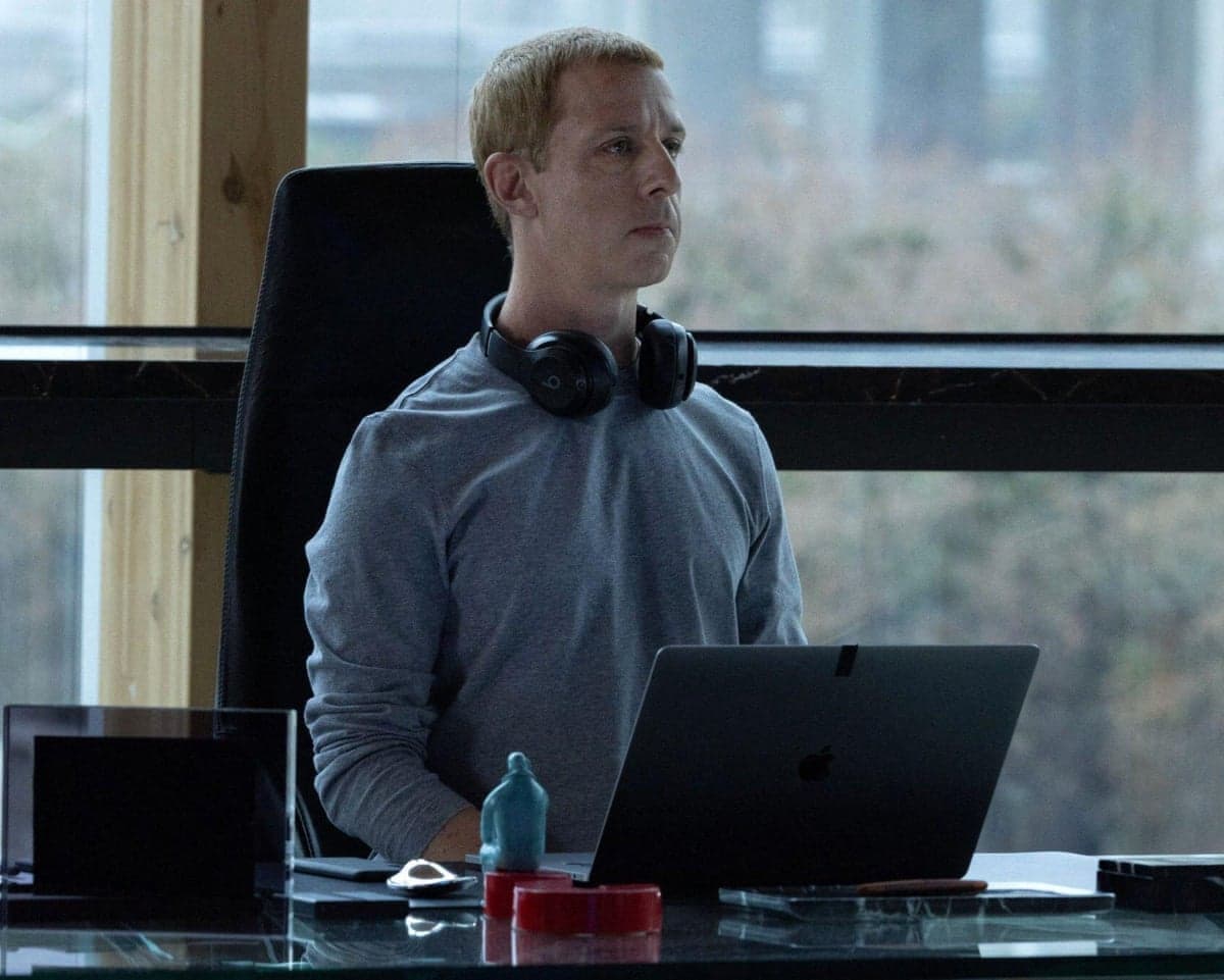 Jeremy Strong as Mark Zuckerberg sits behind a desk with an open laptop