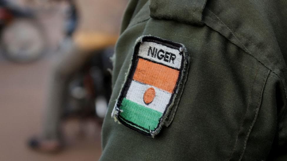 A close-up shot of a badge displaying the Nigerien flag, sewn on to a military uniform