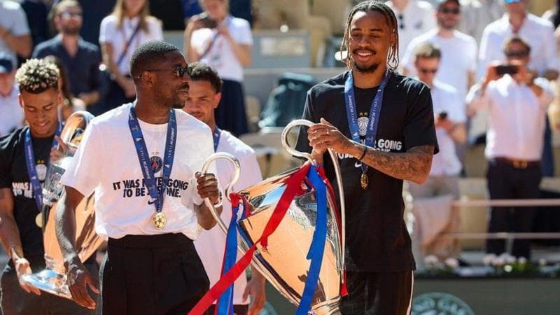 Paris St-Germain players Ousmane Dembele and Bradley Barcola show off the Champions League trophy at the 2026 French Open at Roland Garros