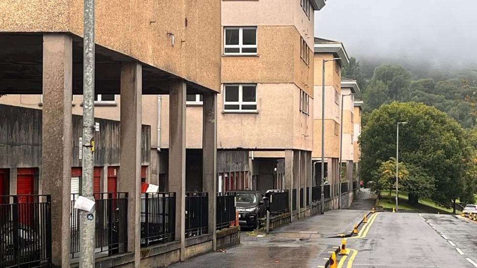 A row of concrete buildings with the fronts supported by concrete pillars as they are built into a steep hillside