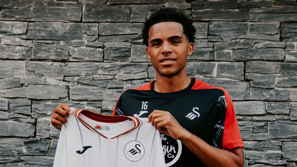 Tom Iorpenda holds a Swansea City shirt up after signing from Huddersfield
