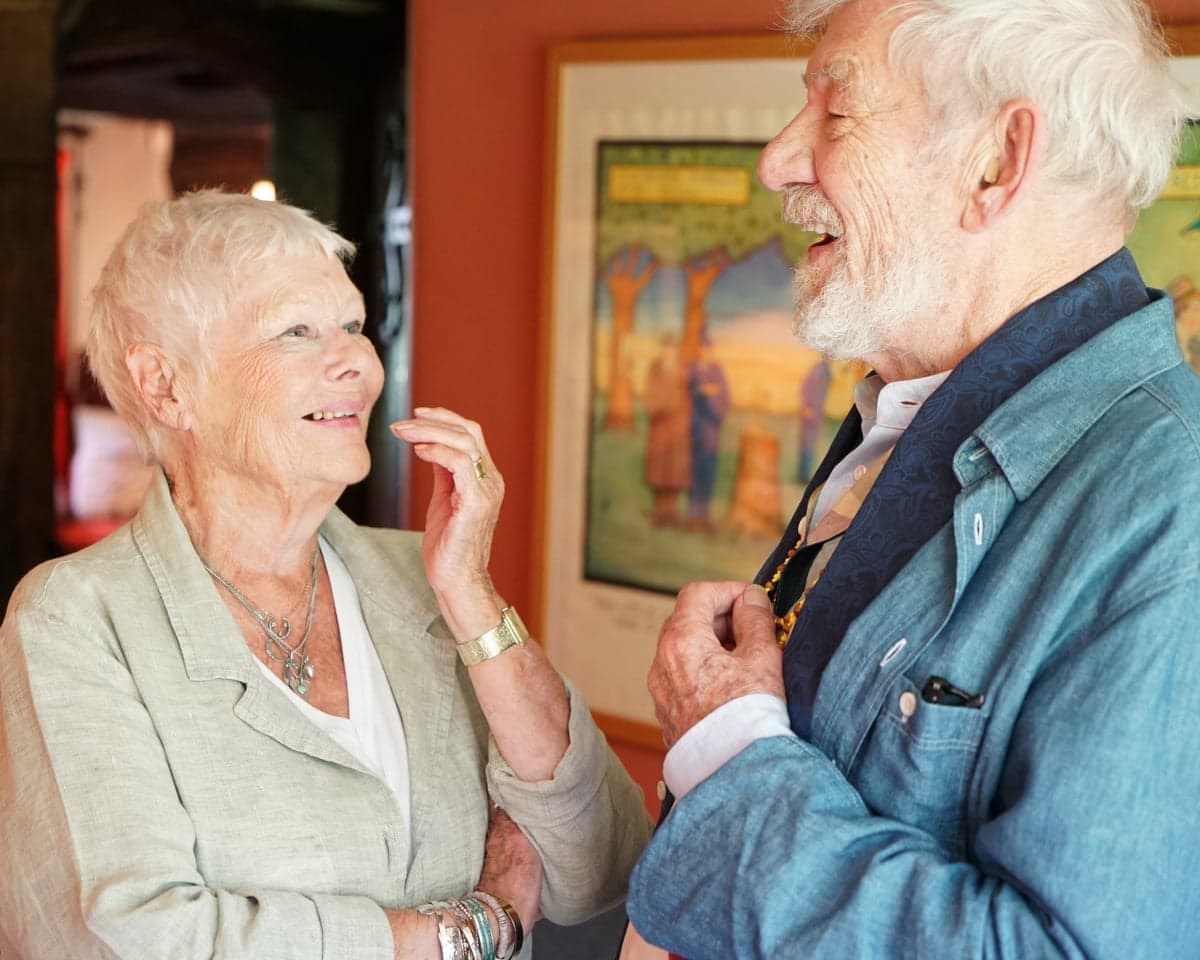 The actors Judi Dench and Ian McKellen smile as they turn towards each other in conversation.