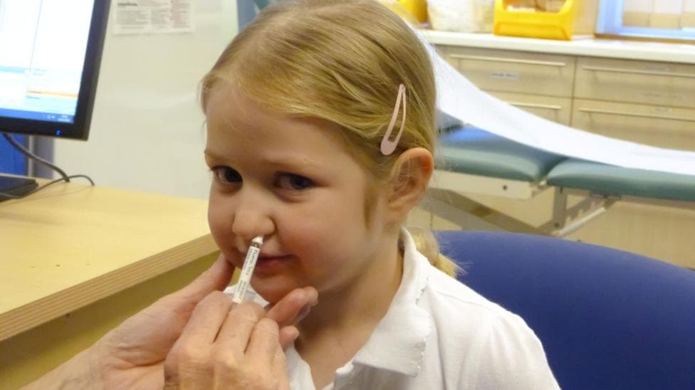 A girl getting her nasal flu vaccine from her GP