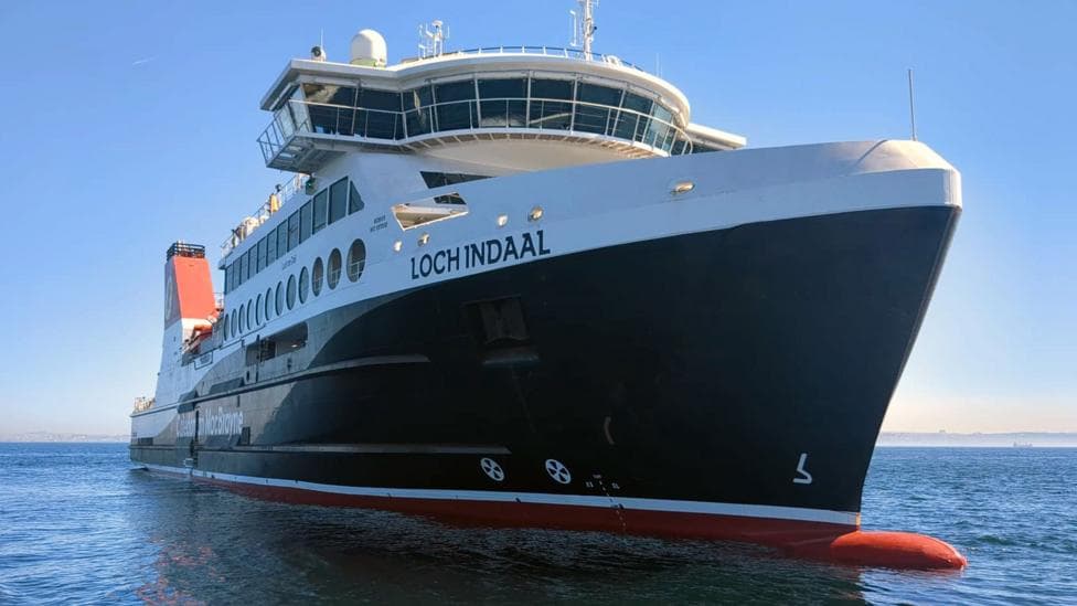 A large black and white ship with red funnels and a red bulbous bow just poking above the water. The name Loch Indaal can be seen on its bow