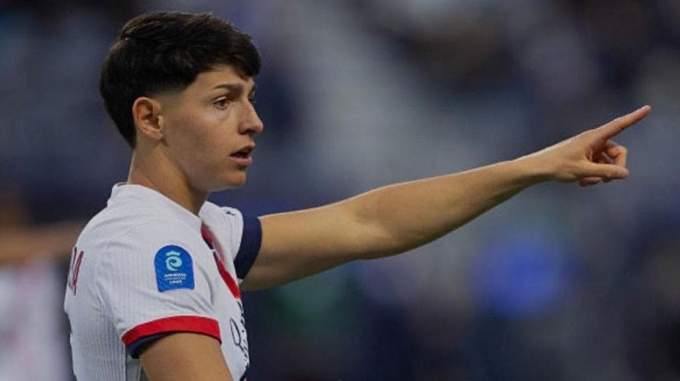 Elisa de Almeida, wearing a white and blue Paris St-Germain kit, points at something during a match