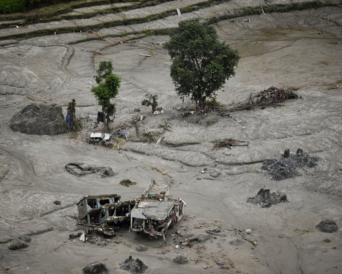 Mud-covered debris and a wrecked building lie in a flood-devastated landscape near Trishuli River, Nepal