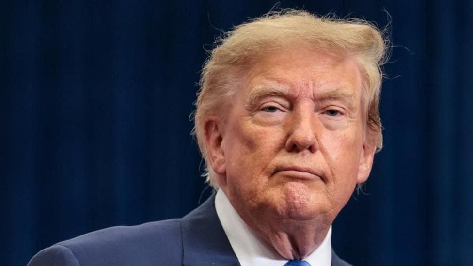 Donald Trump is wearing a blue jacket, blue tie and a white shirt.