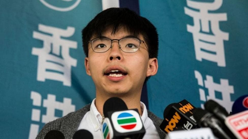 Close up shot of Hong Kong democracy activist Joshua Wong speaking behind a cluster of television news microphones