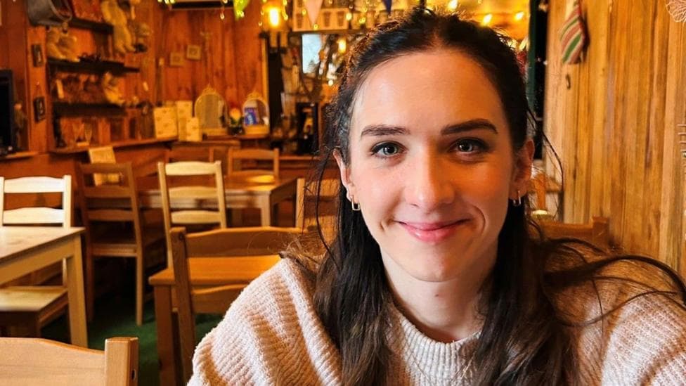 A dark haired woman sat in a warmly lit cafe
