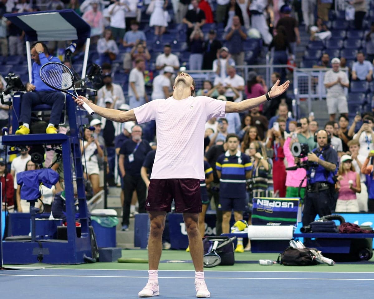 Alexander Zverev raises his arms and looks skyward, celebrating his narrow US Open win.