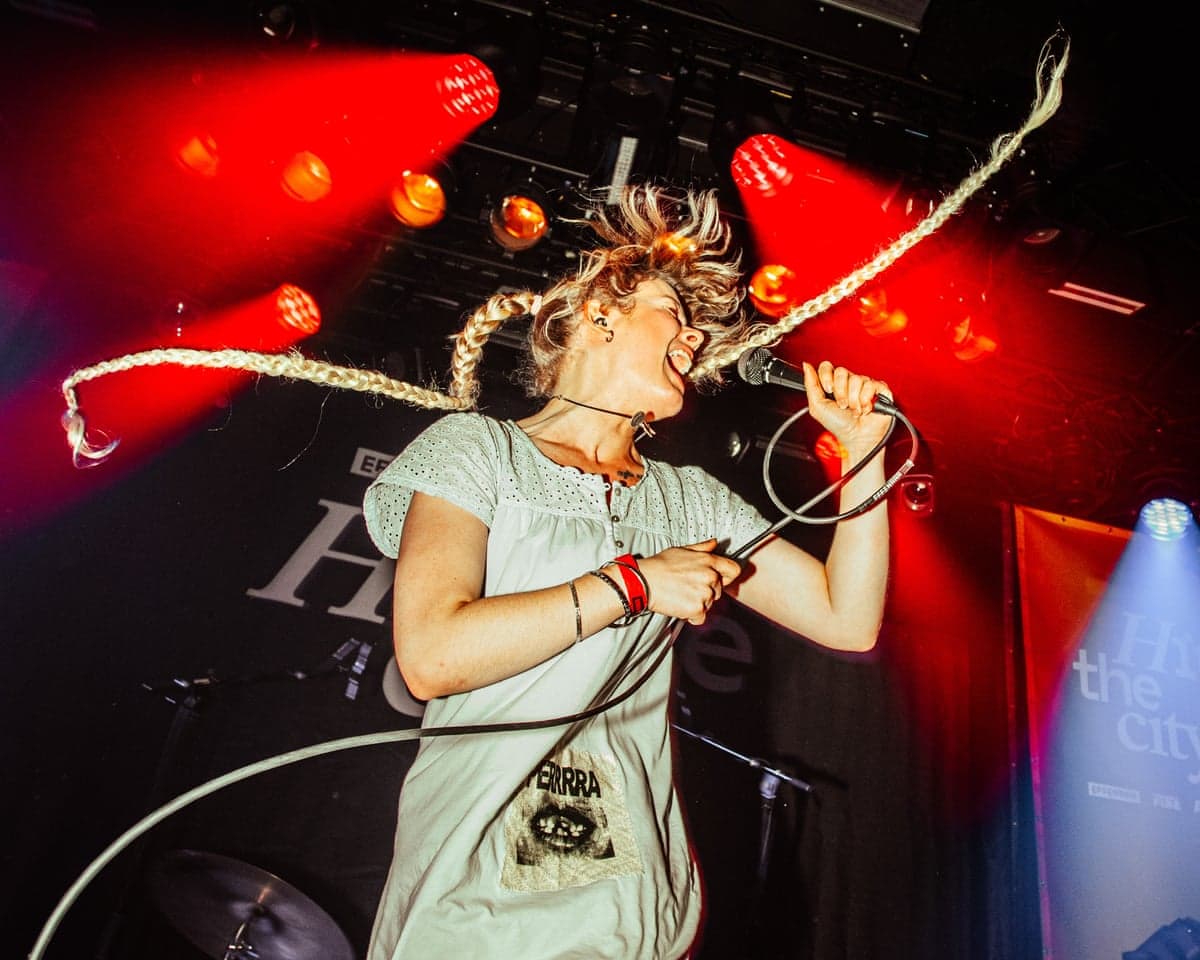 Taylor Zantingh singing into a microphone under red stage lights