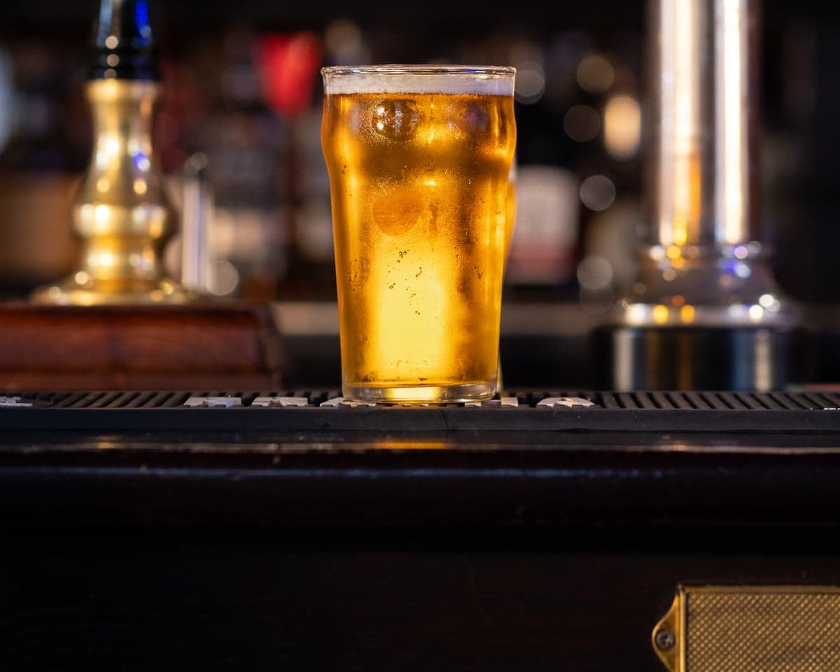 A full pint of lager on a bar counter