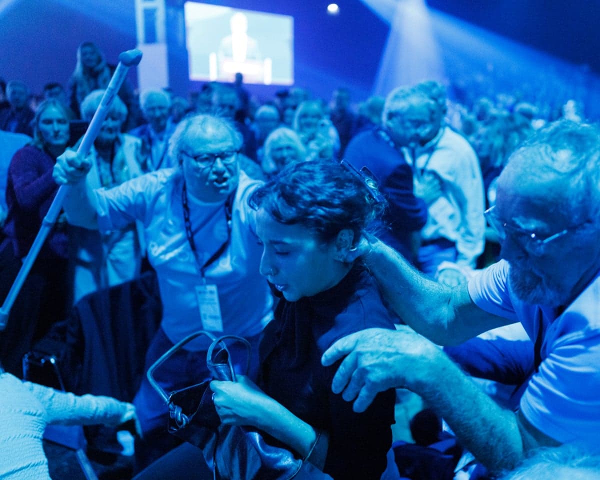 Attendants attempt to remove a heckler during Reform UK leader Nigel Farage's keynote speech on the second day of Reform UK conference at NEC in Birmingham.
