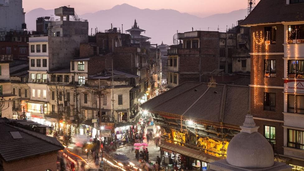 A buzzing hive of activity with shops and vehicles lit-up at an intersection in Kathmandu, the capital of Nepal