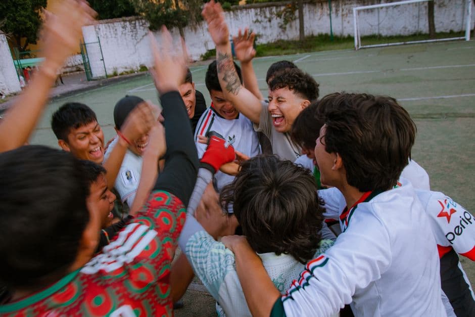 A group of young soccer players celebrating a victory on an outdoor field.