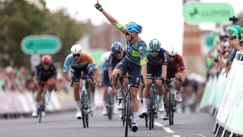 Racer Tim Merlier points a finger in the air to celebrate winning a stage at the Tour of Britain