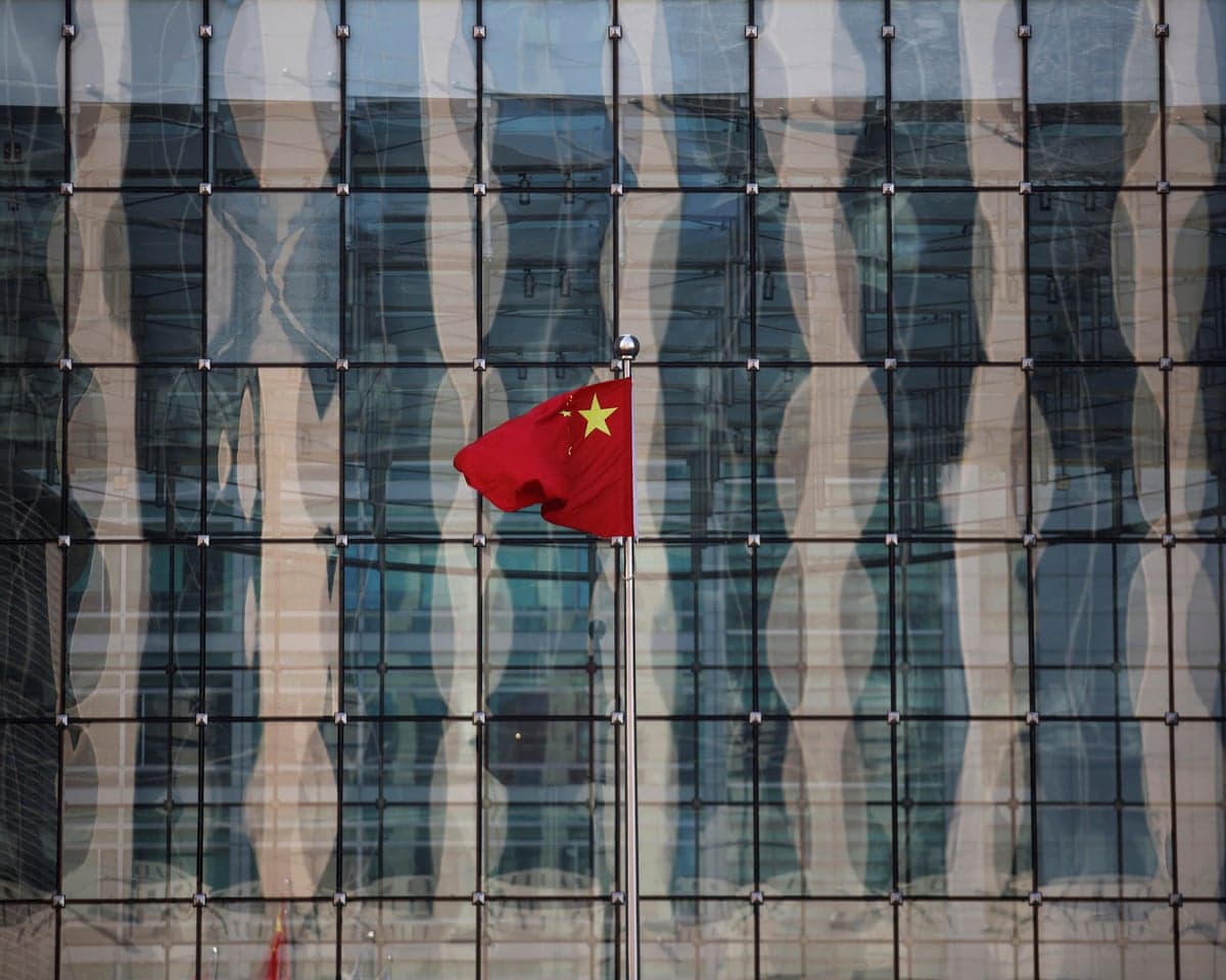 A Chinese national flag flutters at the headquarters of a commercial bank on a financial street near the headquarters of the People's Bank of China in central Beijing