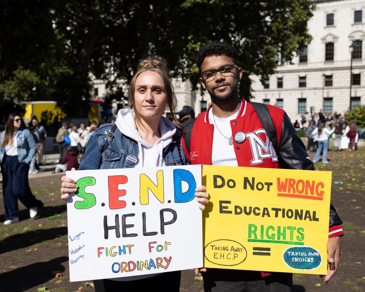 Two people hold up signs expressing support for Send provision in UK schools