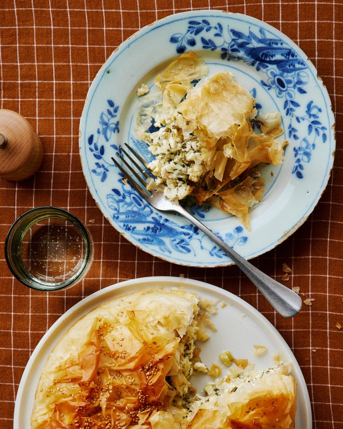 Cheese and spring onion pie with a slice cut out, with other items on a table