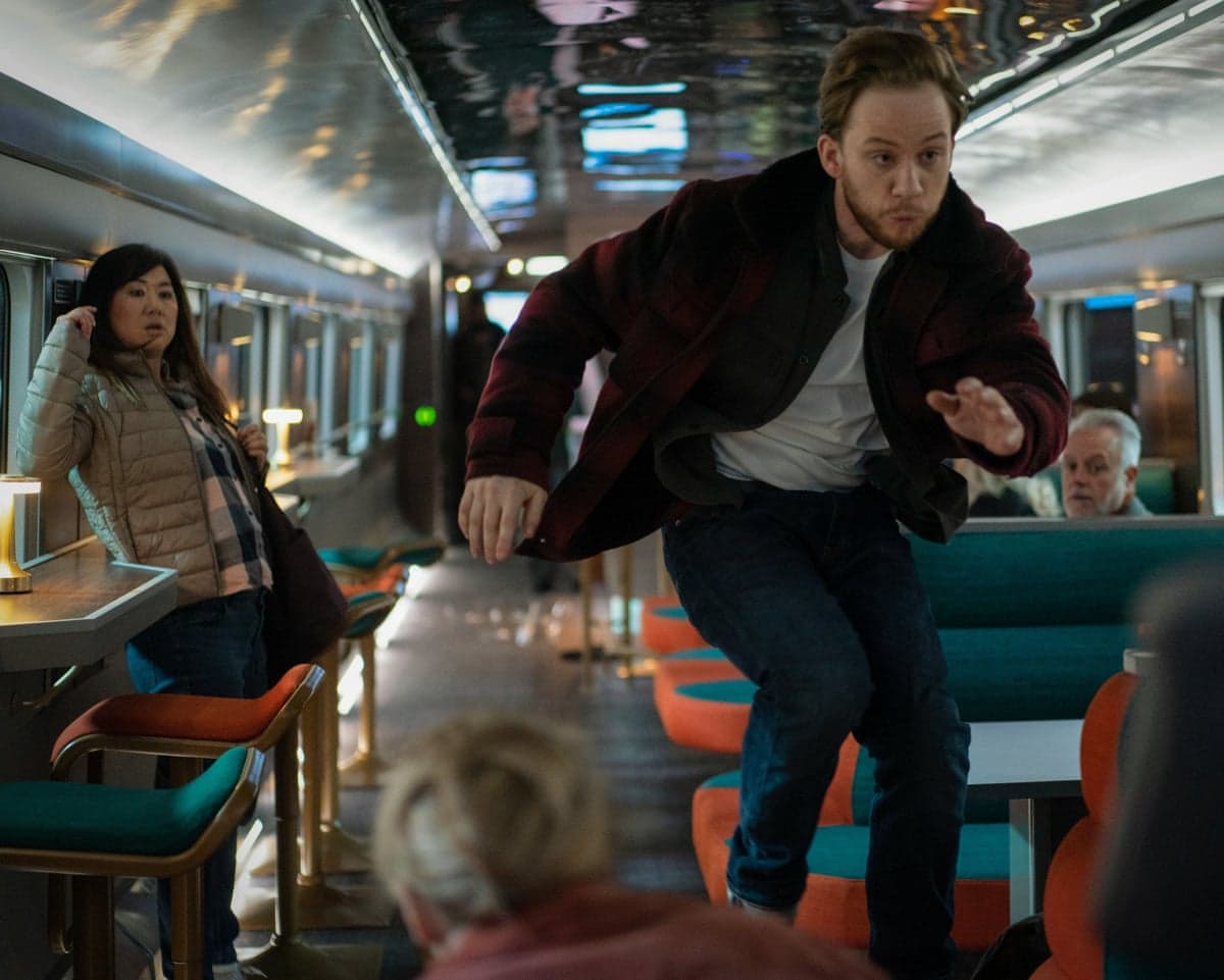 An actor, watched by others, leaps into action in a train carriage in the drama Nightsleeper