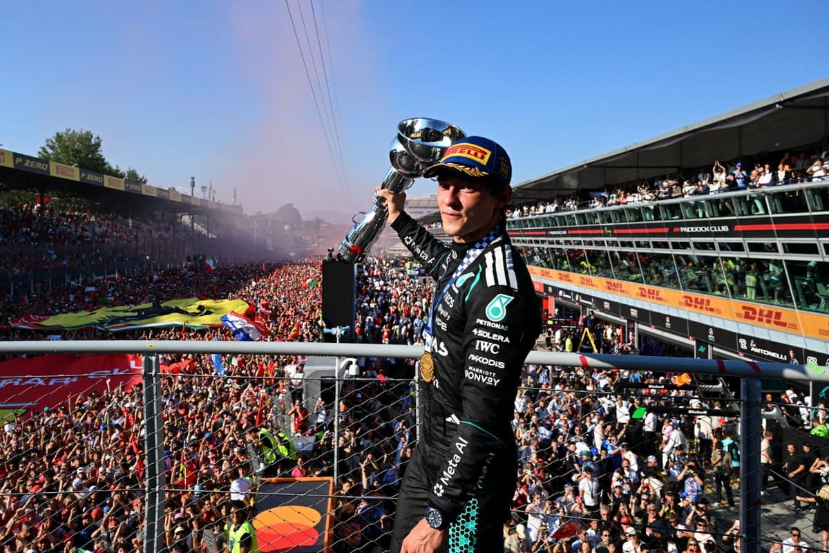 Kimi Antonelli holds a large trophy aloft on the podium above the crowds at the Italian Grand Prix.