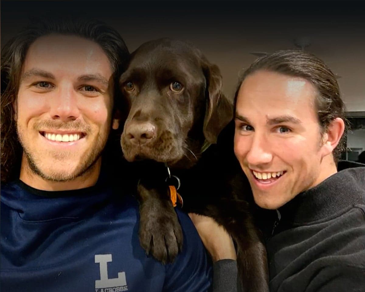 Callum and Jake Robinson smiling for a photo with a brown labrador between them