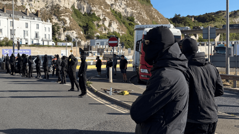 Black-clad and masked demonstrators blocking roads in Dover during a protest.