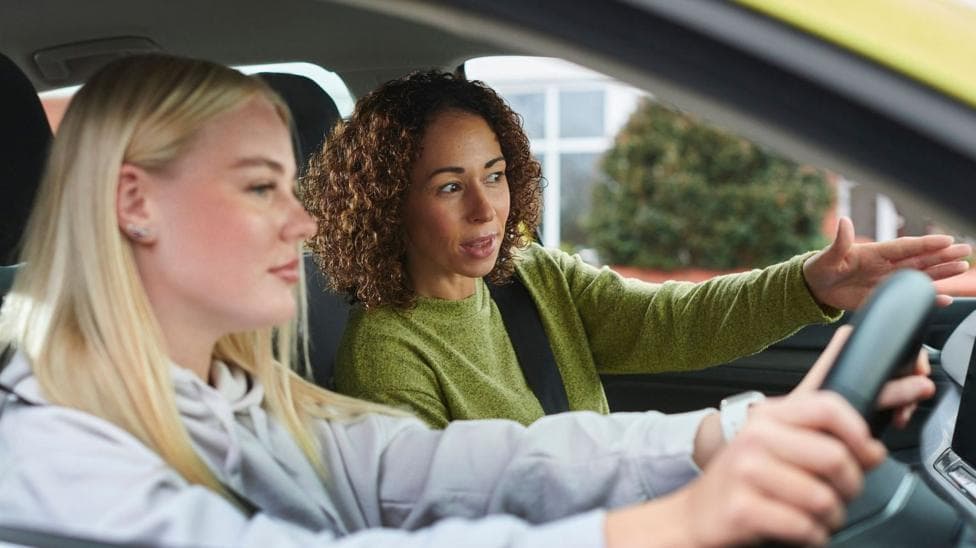 A learner driver and her instructor in a car